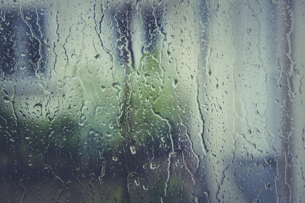 person wiping condensation from window with cloth in winter morning