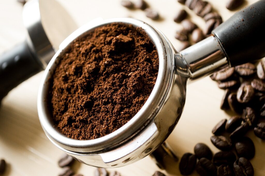 coffee grounds in small bowl next to kitchen trash bin