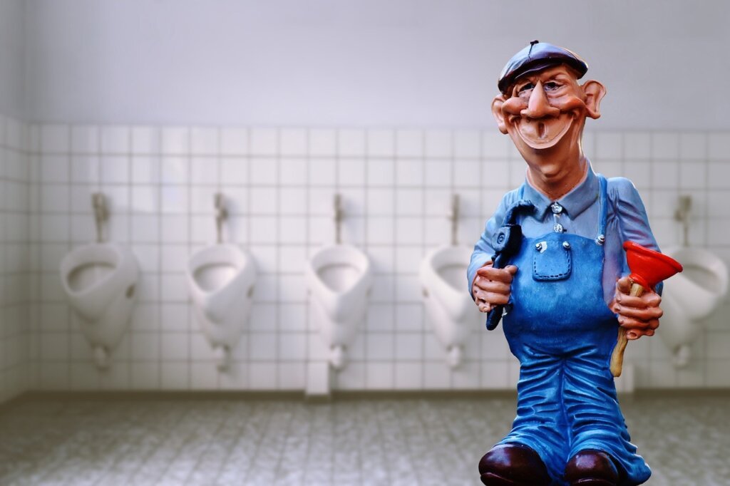 plumber using drain snake tool in kitchen pipe