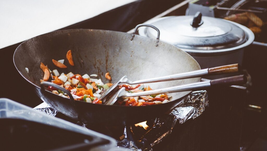 person wiping warm frying pan with kitchen paper right after cooking