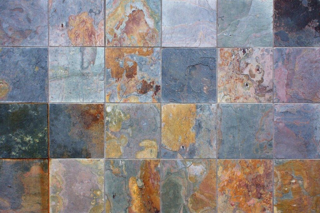 person scrubbing tile grout with old toothbrush and bleach solution wearing rubber gloves