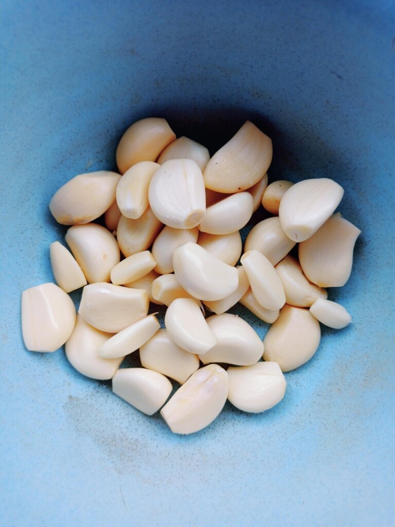 peeled garlic cloves soaking in bowl of water