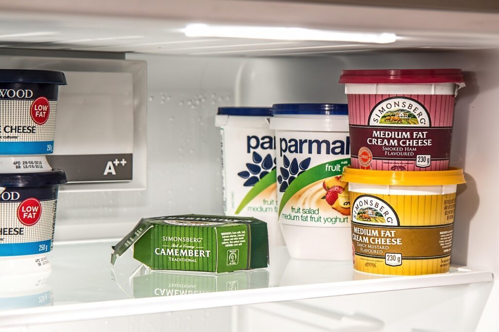 cleaning refrigerator shelf with damp cloth, bright kitchen background