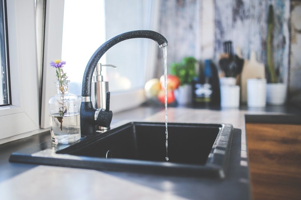 sink cabinet pipe gap with silicone caulk being applied