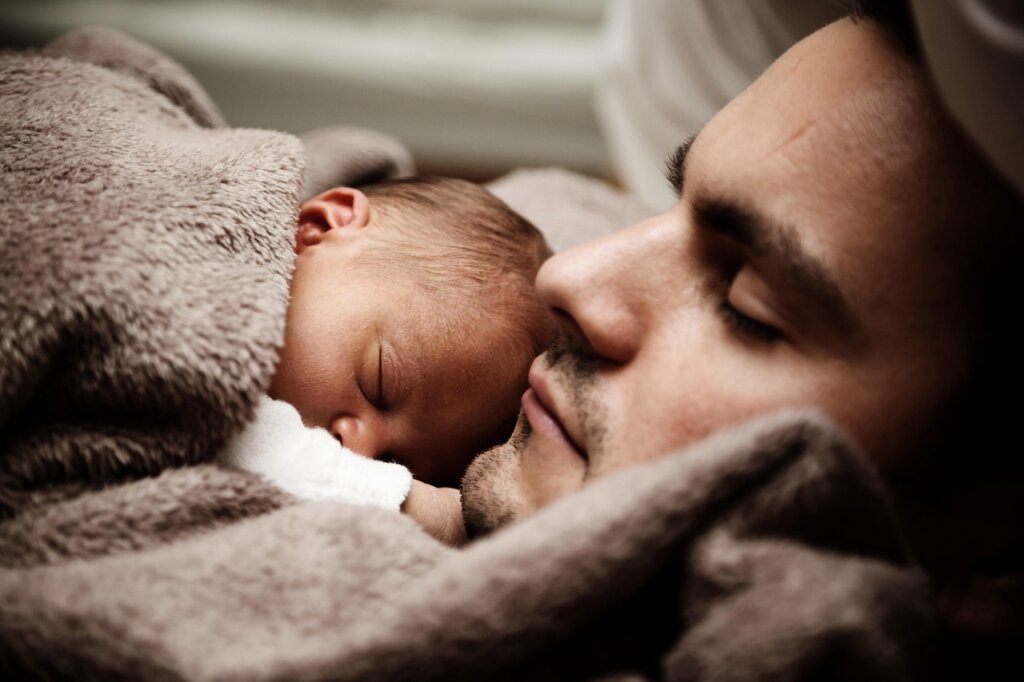 father adjusting air conditioner temperature with child in arms summer home