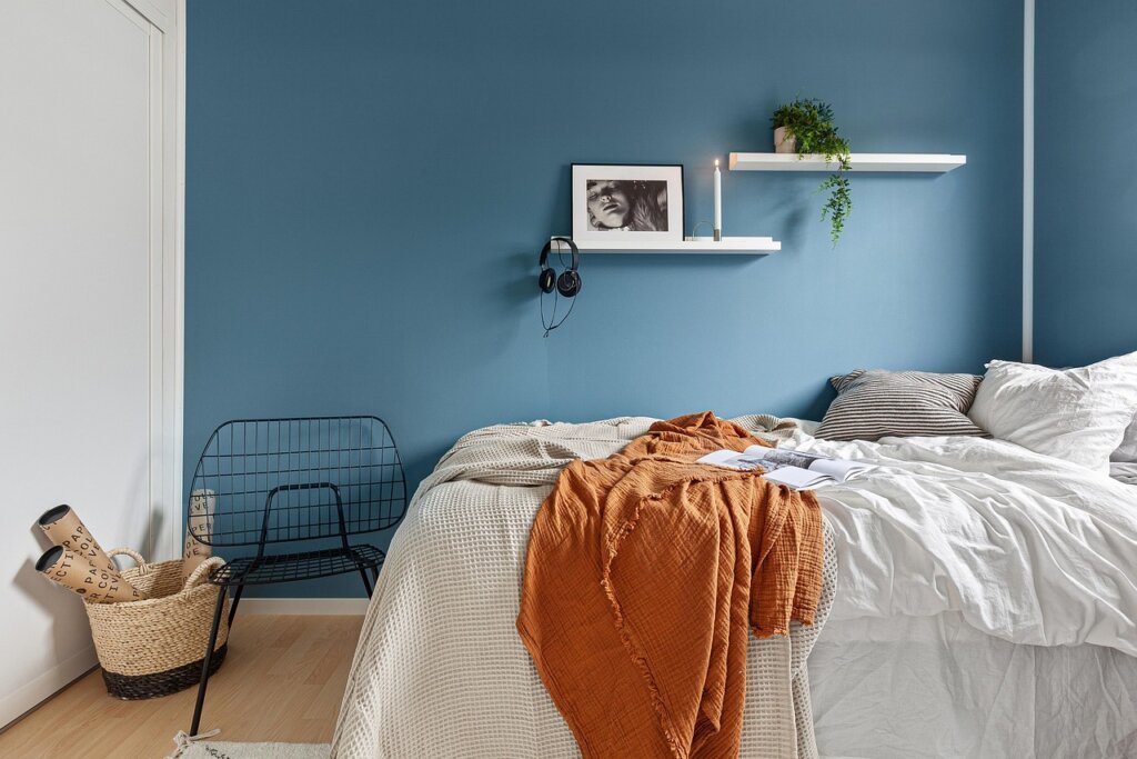 low profile bed frame with tall wall shelves in minimalist bedroom