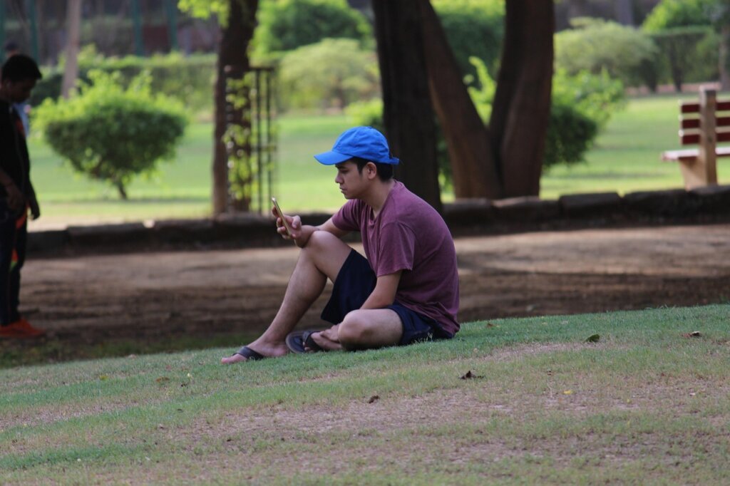 person sitting in outdoor park applying homemade spray repellent casually