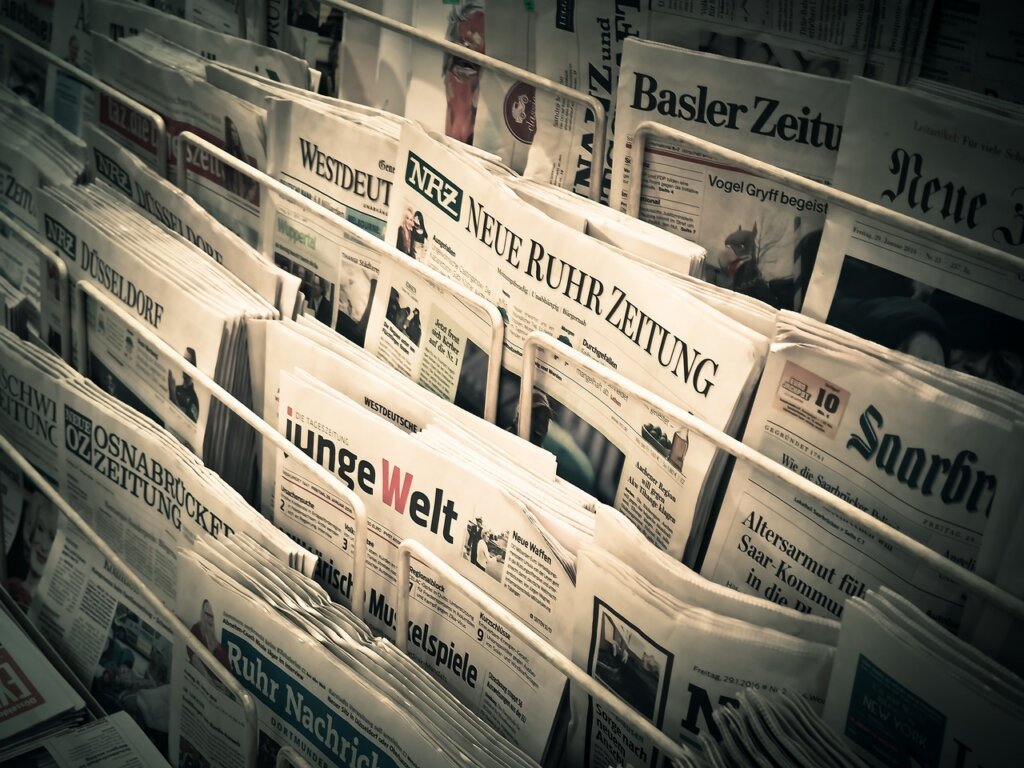 hand wearing rubber gloves wringing out damp newspaper