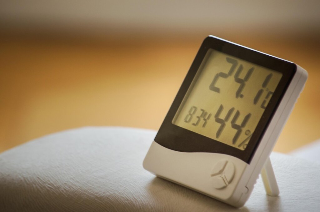 small digital hygrometer thermometer on desk showing indoor humidity